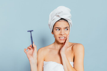 Wall Mural - A woman is holding a razor in her hand while standing in a bathroom