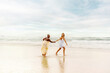 © Alberto - multiracial couple of two girls playing and walking together on the beach shore in summer.