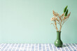 Green vase of dry flower on blue tile table. mint wall background