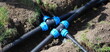 © H_Ko - Connecting HDPE plastic water pipes in garden. Irrigation system and plastic pipes in ground