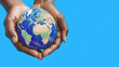 © polack - Afro person holds the Earth between their hands isolated on light blue background. Concept of responsibility and care for the planet, with copy space
