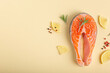 © Foodlovers - Raw fresh fish salmon steak top view on beige pastel background with rosemary, lemon wedges and spices