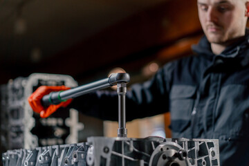 close-up At a service station in the hands of a master a device for tightening bolts works with bolts on the engine