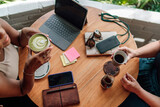 Fototapeta Nowy Jork - Two woman in casual meeting sharing moment over drinks, atmosphere suggests relaxed coffee shop setting with laptop computer and smartphones, indicating a blend of leisure and productivity..