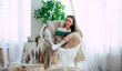 Happy lovely relaxed trendy woman with long healthy hair reads a book in stylish clothes in the modern living room while sitting on hanging chair.
