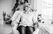 White and black photo of sad thoughtful mature woman looking away while sitting at home on the chair
