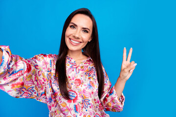 Sticker - Photo of cheerful positive lady dressed print blouse tacking selfie showing v-sign isolated blue color background