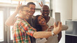 Diverse businesspeople making funny faces while taking a selfie together in a creative office. Group of happy businesspeople celebrating their success on social media.
