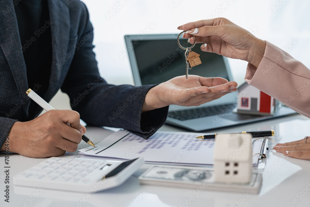 The house and land purchase concept is handing over the keys and house to the customer after agreeing to a home purchase contract and loan agreement. Conversation with real estate agent, close-up phot