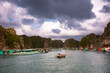 Floating fishing village in sea bay in Vietnam, boats and islands under dramatic sky