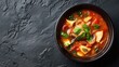 Thai spicy soup with chicken and vegetables in bowl on dark background