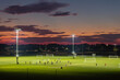 Illuminated public sports arena in North Port, Florida with people playing soccer game on grass football stadium at sunset. Outdoor activities concept