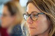 © cff999 - close-up portrait, a woman wearing glasses engages in conversation with her team during a meeting in an office setting