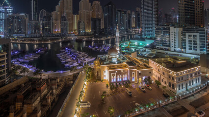 Wall Mural - Yachts in Dubai Marina flanked by the Al Rahim Mosque and residential towers and skyscrapers aerial night to day timelapse.