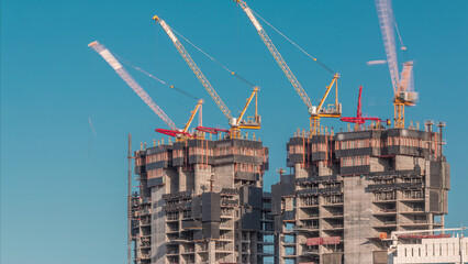 Wall Mural - Aerial view of a skyscraper under construction with huge cranes timelapse in Dubai marina.