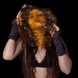 Gothic and beautiful girl holding a yellow cellophane on her face isolated on black background