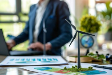 Poster - A blurred male professional works near a wind turbine model, symbolizing business and renewable energy