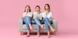 © Pixel-Shot - Surprised young women with laptop sitting on sofa against color background. Online shopping concept