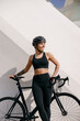 Smiling woman cyclist in protective gear standing with her bike while training outdoors 