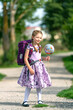 blondes glückliches sechsjähriges Mädchen mit Schultüte und Schulrucksack, erstklässlerin, sonniger tag, schulanfang, ganz körper