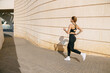Fit woman athlete in sportswear is running on modern buildings background. Active lifestyle concept