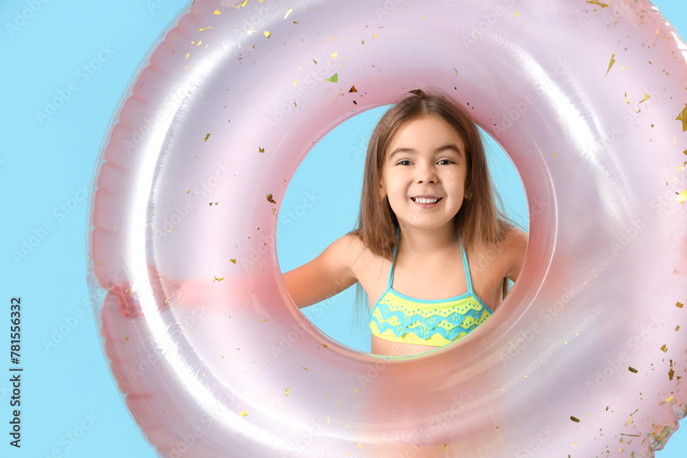 Cute little girl with inflatable ring on blue background