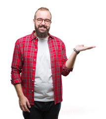 Sticker - Young caucasian hipster man wearing glasses over isolated background smiling cheerful presenting and pointing with palm of hand looking at the camera.