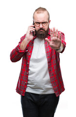 Sticker - Young caucasian hipster man talking on smartphone over isolated background with open hand doing stop sign with serious and confident expression, defense gesture