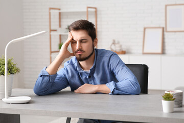 Canvas Print - Tired young businessman at table in office