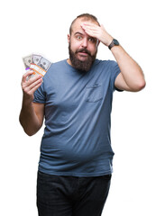 Sticker - Young hipster man holding bunch of money over isolated background stressed with hand on head, shocked with shame and surprise face, angry and frustrated. Fear and upset for mistake.