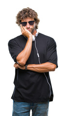 Wall Mural - Handsome hispanic man listening to music wearing headphones over isolated background thinking looking tired and bored with depression problems with crossed arms.