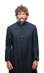 Poster - Handsome hispanic catholic priest man over isolated background sticking tongue out happy with funny expression. Emotion concept.