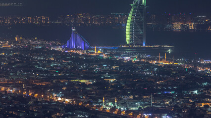 Wall Mural - Aerial view of Dubai city skyline at night with illuminated burj al arab hotel timelapse.