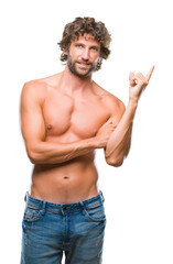 Canvas Print - Handsome hispanic model man sexy and shirtless over isolated background with a big smile on face, pointing with hand and finger to the side looking at the camera.