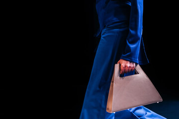 Sticker - Woman wearing blue outfit and holding a stylish white minimalist handbag. Fashion show collection