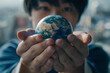 © MarGa - Asian man Holding a Small Globe close-up, Concept of Care for planet and Earth Day
