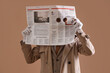 © Pixel-Shot - Male spy holding newspaper with holes on brown background