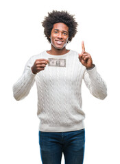 Sticker - Afro american man holding one dollar over isolated background surprised with an idea or question pointing finger with happy face, number one