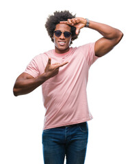 Sticker - Afro american man wearing sunglasses over isolated background smiling making frame with hands and fingers with happy face. Creativity and photography concept.