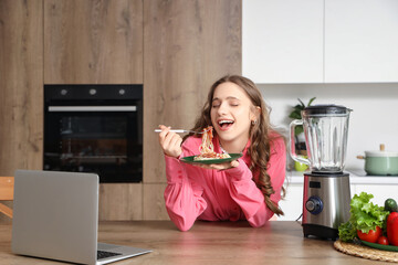 Poster - Young woman eating tasty pasta in kitchen