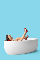 Sticker - Beautiful woman with heels in bathtub on blue background