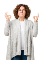 Wall Mural - Beautiful middle ager senior woman wearing jacket and glasses over isolated background relax and smiling with eyes closed doing meditation gesture with fingers. Yoga concept.