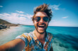 Young happy man wearing sunglasses taking selfie on the seashore. Cheerful man traveling.