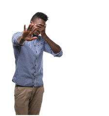 Canvas Print - Young african american man wearing blue shirt covering eyes with hands and doing stop gesture with sad and fear expression. Embarrassed and negative concept.