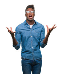 Sticker - Young african american man over isolated background crazy and mad shouting and yelling with aggressive expression and arms raised. Frustration concept.