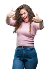 Sticker - Beautiful brunette curly hair young girl wearing pink sweater over isolated background approving doing positive gesture with hand, thumbs up smiling and happy for success. Looking at the camera.