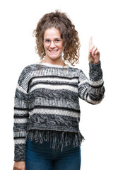 Canvas Print - Beautiful brunette curly hair young girl wearing glasses over isolated background showing and pointing up with finger number one while smiling confident and happy.