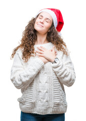 Sticker - Young brunette girl wearing christmas hat over isolated background smiling with hands on chest with closed eyes and grateful gesture on face. Health concept.