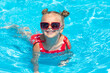 Child in swimming pool. Tropical vacation for family with kids. Little girl wearing red swimsuit playing in outdoor pool of exotic island resort. Water and swim fun for children