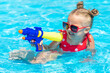 Laughing child playing with water gun in outdoor swimming pool on summer day. Pool toys and water fun for family with children. Summer vacation with kids. Active outdoor sport for preschooler.